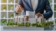 © Gambar Upi - real estate development. businessman or architect showing new business office complex scale model