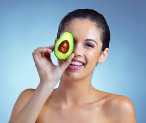 Happy portrait, woman and avocado for skincare with facial glow, diy mask and nutrition in studio. Model smile, face and omega 3 food with dermatology, vitamin c diet and shine by blue background