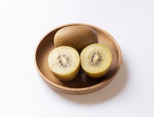 Close up of three Kiwi fruits with half-cut twos on wooden bowl and white floor, South Korea
