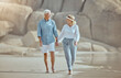 © peopleimages.com - Mature, couple and walking on beach with love on retirement vacation, romance and together with years of commitment. Man, woman and holding hands by ocean on holiday, happy and bonding with embrace.