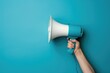 © MrHamster - Hand holding a blue and white megaphone against a blue background