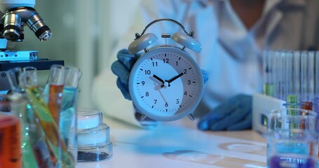 Wall Mural - Laboratory assistant shows vintage alarm clock at workplace