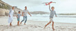 © peopleimages.com - Parents, children and plane toys at beach with running, smile or bonding with love on vacation in summer. Dad, mom and kids on holiday with airplane, games or playful with family in sunshine by ocean
