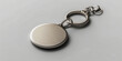 © Na-No Photos - A sleek silver keychain with a round, blank medallion, designed for custom engraving, rests against a minimalist, light gray background.