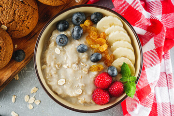 Wall Mural - tasty nutritious oatmeal with fruits and berries on a light stone background