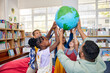 © Rido - School children with teacher holding earth model in a library