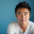 © Zainab - Young Man With Short Dark Hair Smiling Against a Blue Background