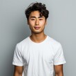 © Zainab - Young Man With Wavy Hair Wearing a White T-Shirt Against a Gray Background