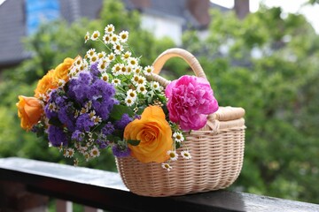 Wall Mural - Wicker basket with beautiful aromatic flowers on balcony railing outdoors