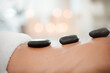 © peopleimages.com - Relax, person and back with hot stone massage at spa for body treatment, skincare and wellness. Hotel, hospitality and client with rock for deep tissue healing, holistic and muscle health at resort