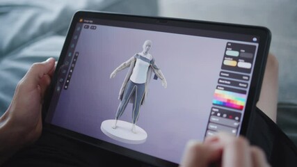 Fototapete - Boy with digital stylus and tablet in hands sits at home, creates 3d models. Focused teenager draws clothes for game character using 3d modeling program. Development and game design concept. Close up.