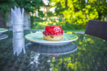 Wall Mural - A small red cake sits on a green plate on a table