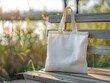 © Kartika - A white canvas bag sits on a wooden bench in a park