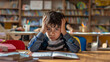 © K KStock - Frustrated elementary school boy sitting in school with a book open