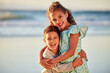 © peopleimages.com - Happy kids, portrait and hug on beach for vacation or holiday with smile, fun and outdoor summer travel. Boy, girl and children siblings laughing at sea for adventure, support and playing in ocean