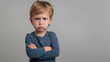 © Natali - Mad male kid, angry little boy standing with his arms crossed, and looking at the camera with upset face expression. Unhappy toddler, studio shot, annoyed and frustrated child emotion