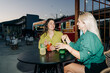 © Ilona - Two women friends sitting at a table in a cafe outside drinking cool drinks.