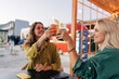 © Ilona - Two women friends sitting at a table in a cafe outside drinking cool drinks.
