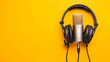 © alfi - Podcasting tools on vibrant yellow background with headphones and microphone in overhead view