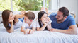 © Lumeez23/peopleimages.com - Happy family, lying and relax with bed for morning, bonding or holiday weekend together at home. Mother, father and children with smile, son and daughter for wake up or comfort in bedroom at house