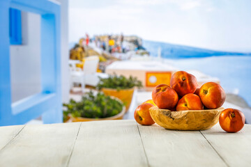 Sticker - Nectarines in wooden bowl on white wooden table. Summer outdoor terrace of a building and blur city and sea background. Copy space for food and drinks and products.