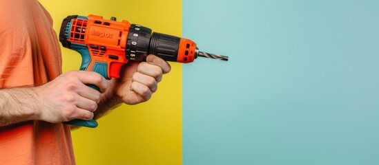 Poster - Man holding power drill against bright yellow and blue background