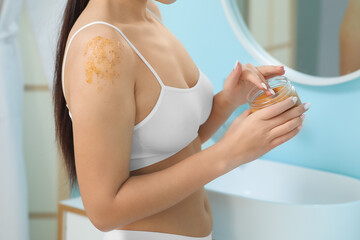 Sticker - Young woman with jar applying body scrub on shoulders, closeup