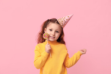 Poster - Cute little girl in holiday cap with lollipop on pink background