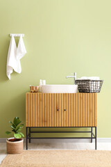 Poster - Clean towels on hooks and wooden chest of drawers with sink near green wall in bathroom