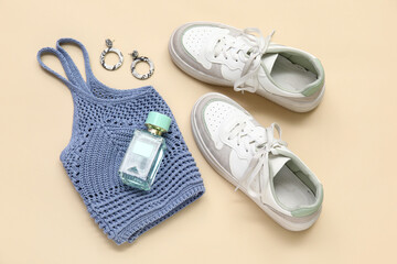 Wall Mural - White sneakers, top, bottle of perfume and earrings on beige background