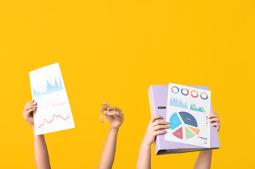 Poster - Female hands with financial graphics, folder and hourglass on yellow background