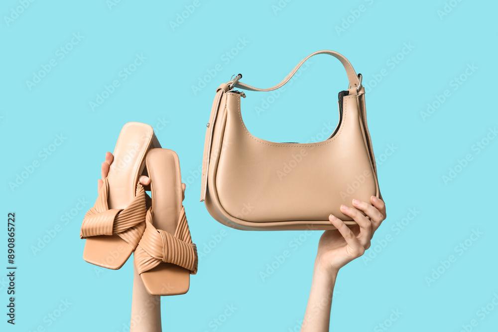 Female hands with bag and heeled sandals on blue background