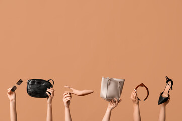 Wall Mural - Female hands with bags, sunglasses, headband and heeled shoes on beige background