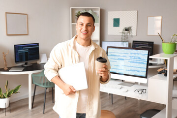 Canvas Print - Handsome programmer with laptop and coffee cup in office