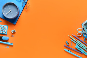 Wall Mural - Frame made of school supplies with alarm clock on orange background. Top view