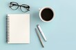 © Fakhrul - A flat lay of a business notebook, glasses, pen, and a cup of coffee on a desk