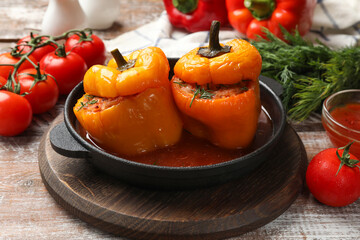 Wall Mural - Tasty stuffed peppers in pan and products on wooden rustic table, closeup