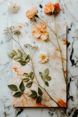 Wall Mural - A white marble slab with a variety of flowers and leaves on it. The flowers are orange and yellow, and the leaves are green. The arrangement is simple and elegant, with the flowers