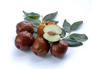 Poster - Close up and top angle view of brown jujube fruits with one half cut and leaves on white floor, South Korea
