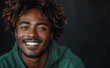 Happy young man wearing green sweatshirt, laughing, smiling, isolated on dark background