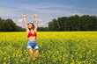 © Anton Belovodchenko - An adult happy woman in a red top and denim shorts jumps and makes a wheel element in a yellow rapeseed field. Motion blur effect.