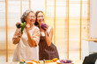© CandyRetriever  - Happy Asian family cooking and having dinner together at home. Senior mother and adult daughter enjoy and fun with healthy lifestyle singing and dancing together during preparing food in the kitchen.