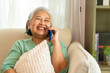 © CandyRetriever  - Happy Asian senior mature woman relaxing on sofa in living room speaking on mobile phone with family. Elderly grandmother enjoy smart indoor lifestyle with wireless technology and digital device.