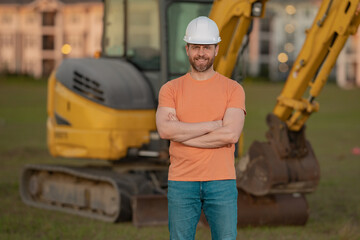 Wall Mural - Builder, construction worker in helmet at construction site. Industry engineer worker in hardhat near bulldozer or digger tractor. Concept of construction industry. Construction site manager.