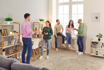 Company of cheerful smiling people friends or coworkers meeting in the living room together, talking and sharing news and stories with each other gathering at party at home. Friendship concept.