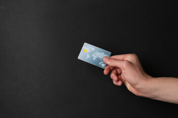 Canvas Print - Man holding credit card on black background, closeup