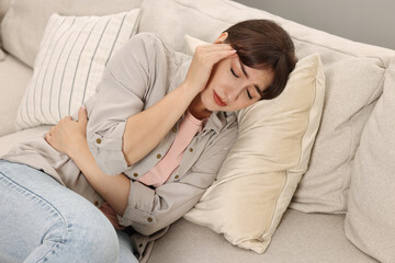 Sticker - Upset woman suffering from headache on sofa at home