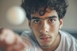 © ChaoticMind - A young man is pictured with a serious expression, focused intently on reaching towards a ping pong ball suggesting a moment of concentration and determination in the game.