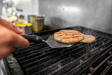 Canvas Print - Close-up view of grilled burger patties being flipped on a grill