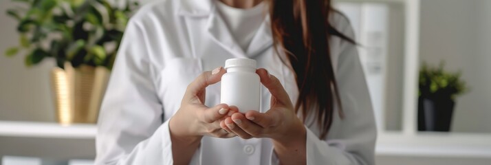 Poster - Female doctor holding a white medicine bottle in a bright office. Pharmaceutical care and medical service concept.